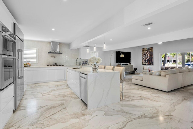 kitchen featuring recessed lighting, a sink, stainless steel appliances, wall chimney range hood, and modern cabinets