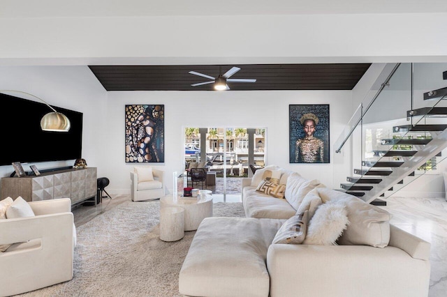 living area with stairway, baseboards, and ceiling fan