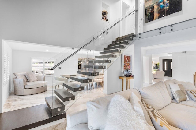 living room with marble finish floor, stairs, and a high ceiling