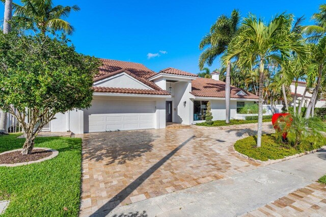 mediterranean / spanish house with stucco siding, a tiled roof, driveway, and a garage