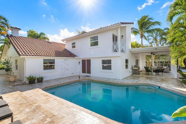 rear view of house featuring a patio, a balcony, an outdoor pool, stucco siding, and a tile roof