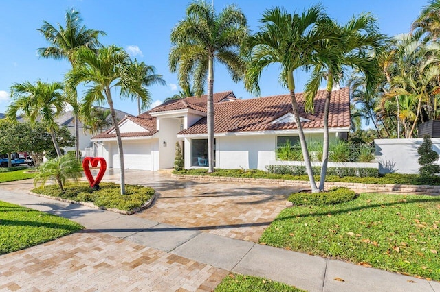mediterranean / spanish house with a tile roof, decorative driveway, a garage, and stucco siding