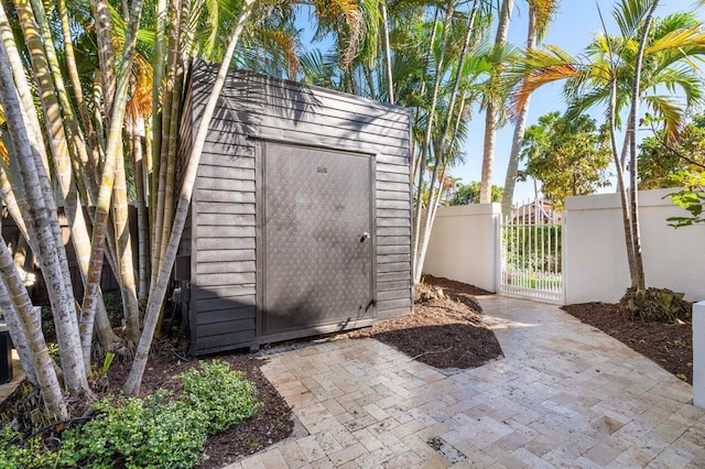 view of shed featuring fence and a gate