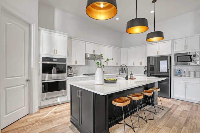 kitchen with white cabinetry, an island with sink, sink, hanging light fixtures, and stainless steel appliances