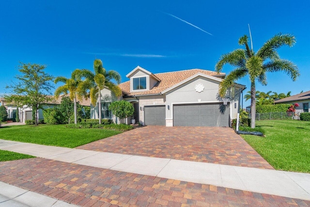 mediterranean / spanish-style house featuring a garage, decorative driveway, a front yard, and stucco siding