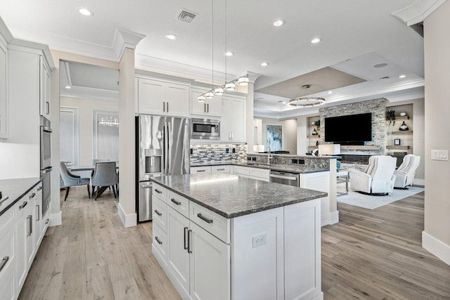 kitchen with visible vents, a kitchen island, ornamental molding, appliances with stainless steel finishes, and open floor plan