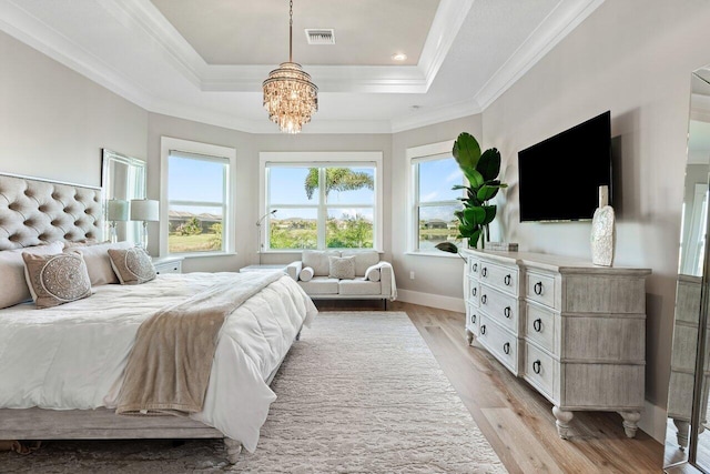 bedroom with light wood-type flooring, visible vents, a raised ceiling, and crown molding