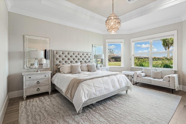 bedroom with a raised ceiling, crown molding, wood finished floors, and baseboards