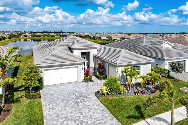 single story home featuring a residential view, a tiled roof, stucco siding, decorative driveway, and a garage