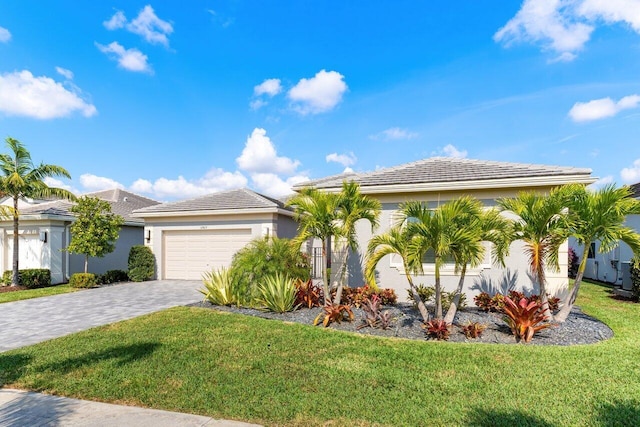 view of front of house with stucco siding, a tile roof, decorative driveway, a front yard, and a garage