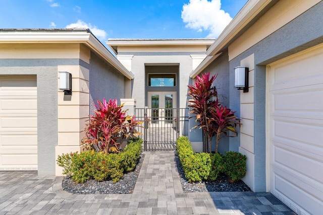 view of exterior entry with stucco siding and an attached garage