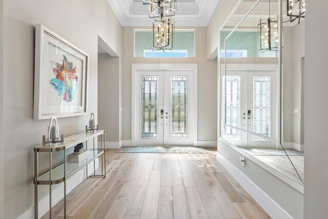 foyer featuring a notable chandelier, ornamental molding, wood finished floors, french doors, and baseboards