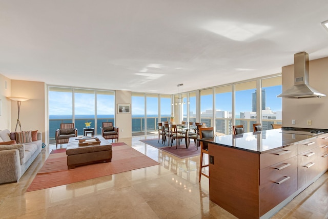 kitchen with expansive windows, a water view, a center island, and wall chimney range hood