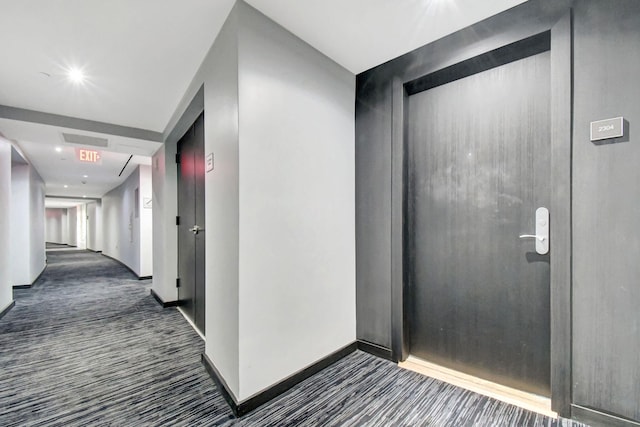 hall featuring dark colored carpet