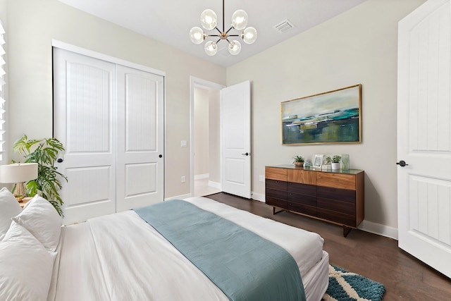 bedroom with baseboards, visible vents, dark wood-type flooring, a chandelier, and a closet