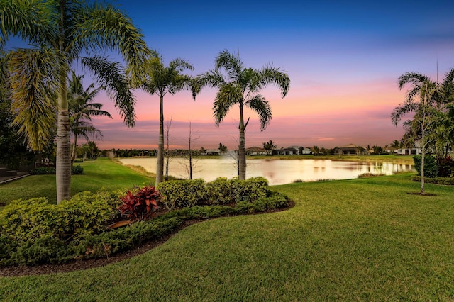 yard at dusk featuring a water view