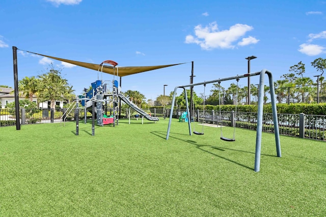 community jungle gym featuring fence and a lawn