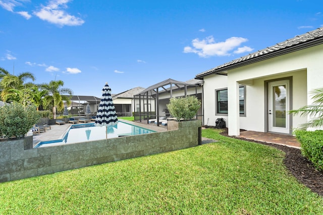 view of pool featuring glass enclosure, a yard, a patio area, and a fenced in pool