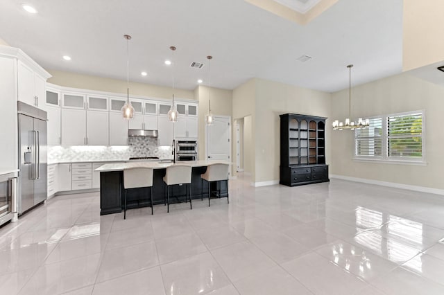 kitchen with stainless steel appliances, light countertops, a kitchen island with sink, white cabinetry, and under cabinet range hood