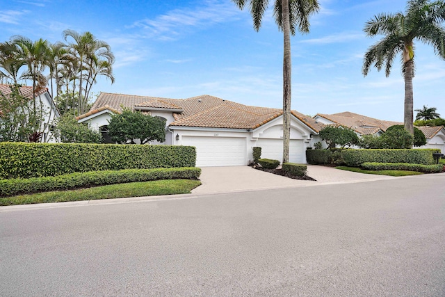 view of front of house with driveway, a tiled roof, an attached garage, and stucco siding