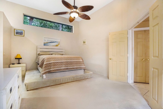 bedroom with light carpet, light tile patterned floors, and a ceiling fan