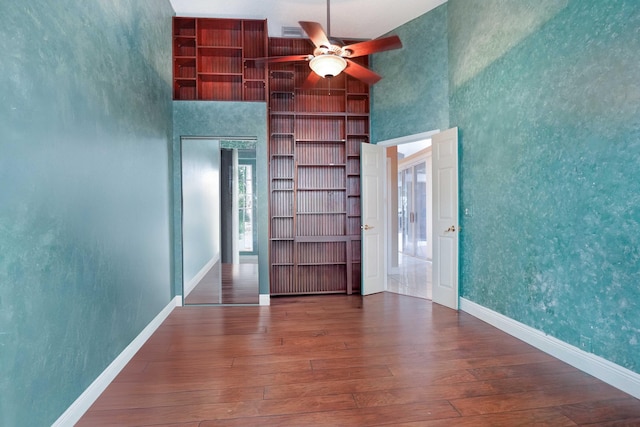 unfurnished room featuring baseboards, dark wood-type flooring, a towering ceiling, and built in features