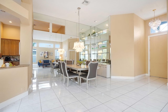 dining area featuring light tile patterned flooring, a towering ceiling, visible vents, and a notable chandelier