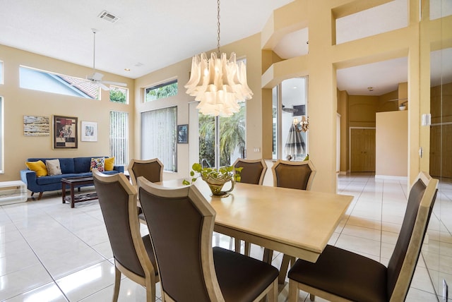 dining room with light tile patterned floors, ceiling fan with notable chandelier, a high ceiling, visible vents, and baseboards