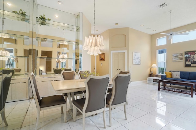 dining space featuring light tile patterned floors, a high ceiling, visible vents, and ceiling fan with notable chandelier