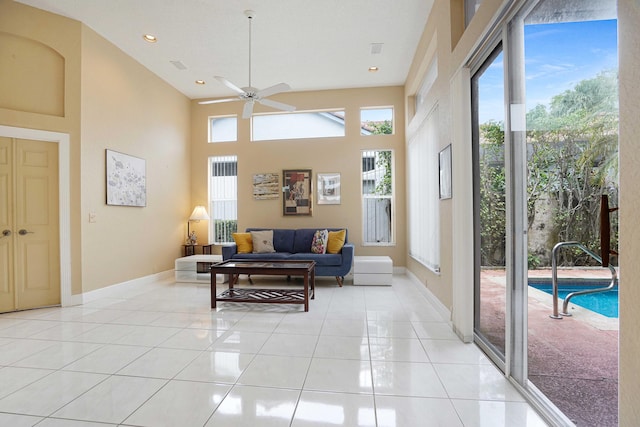 living area with a towering ceiling, recessed lighting, baseboards, and light tile patterned flooring