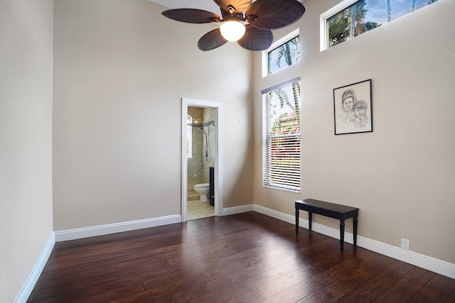 spare room featuring a ceiling fan, dark wood-style flooring, a healthy amount of sunlight, and baseboards