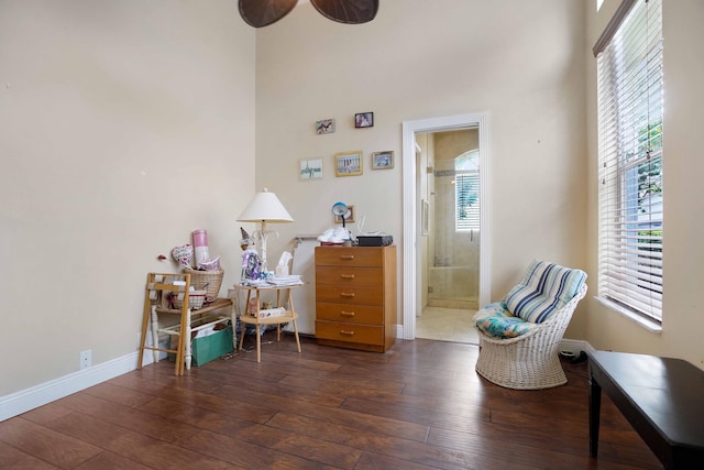 sitting room with a high ceiling, dark wood-style flooring, and baseboards