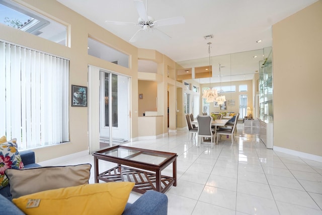 living area with light tile patterned floors, baseboards, visible vents, a ceiling fan, and a towering ceiling