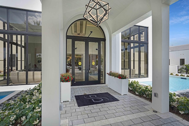 view of exterior entry featuring a patio, french doors, stucco siding, and an outdoor pool