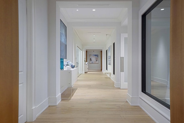 hallway with ornamental molding, light wood-style flooring, and baseboards