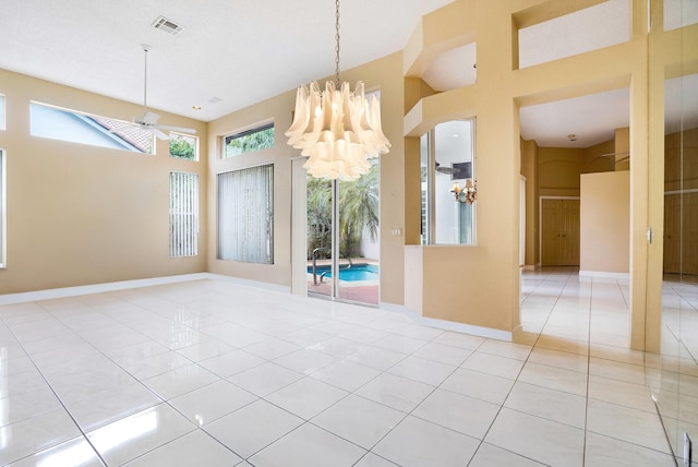 spare room featuring a notable chandelier, visible vents, a towering ceiling, light tile patterned flooring, and baseboards