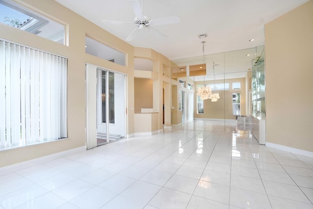 empty room featuring a wealth of natural light, light tile patterned flooring, visible vents, and baseboards