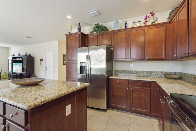 kitchen with light stone countertops, appliances with stainless steel finishes, a center island, and light tile patterned floors