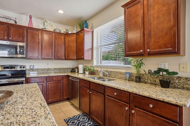 kitchen with sink, light tile patterned floors, stainless steel appliances, and light stone countertops