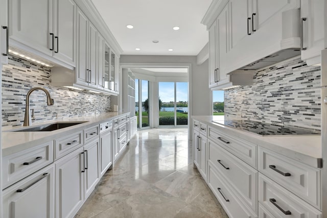 kitchen with white cabinetry, light stone countertops, sink, and black electric stovetop