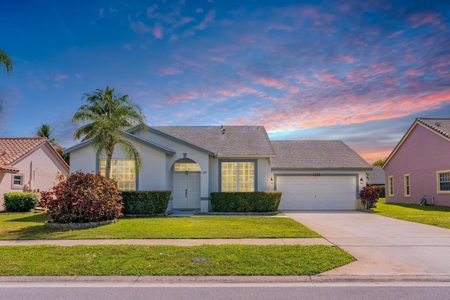 view of front of home with an attached garage, a front yard, concrete driveway, and stucco siding