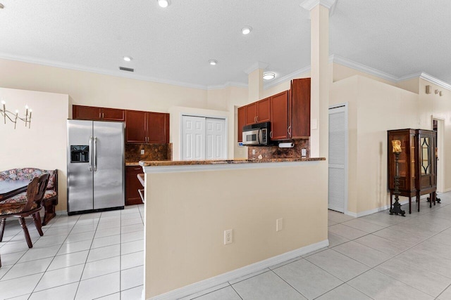 kitchen featuring light tile patterned flooring, ornamental molding, appliances with stainless steel finishes, and dark stone countertops