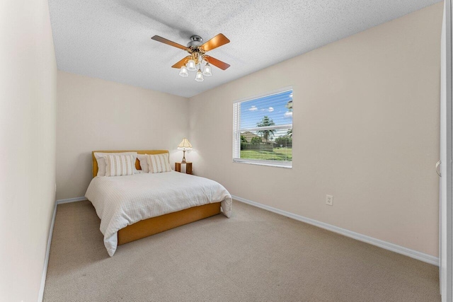 carpeted bedroom with ceiling fan and a textured ceiling