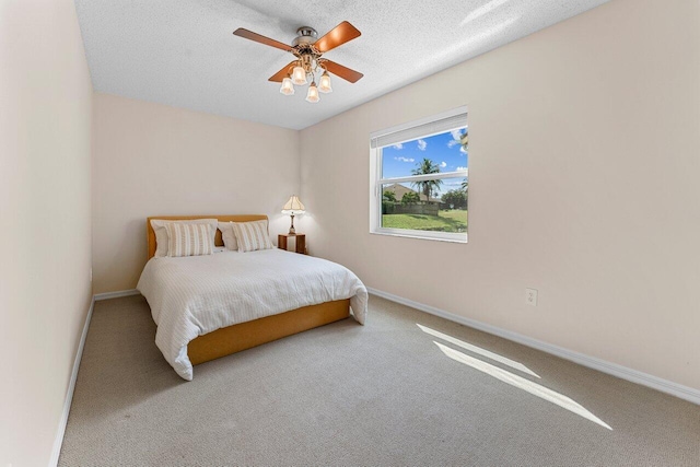 carpeted bedroom with ceiling fan and a textured ceiling