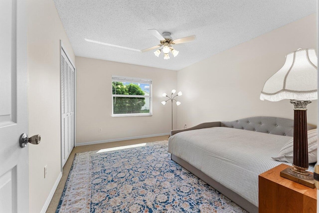 carpeted bedroom with ceiling fan, a closet, and a textured ceiling