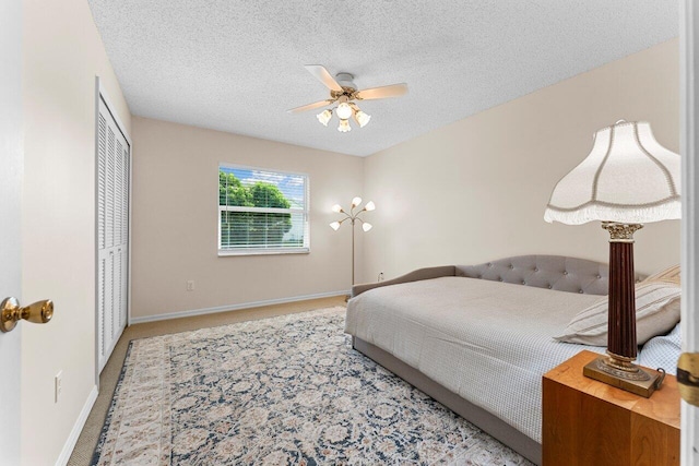 carpeted bedroom featuring ceiling fan, a textured ceiling, and a closet