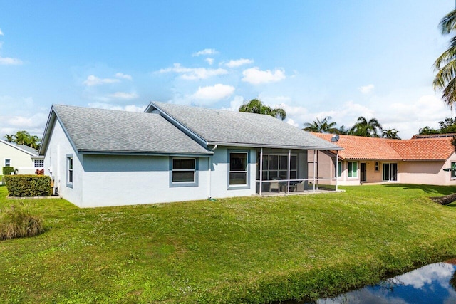 back of property with a lawn and a sunroom