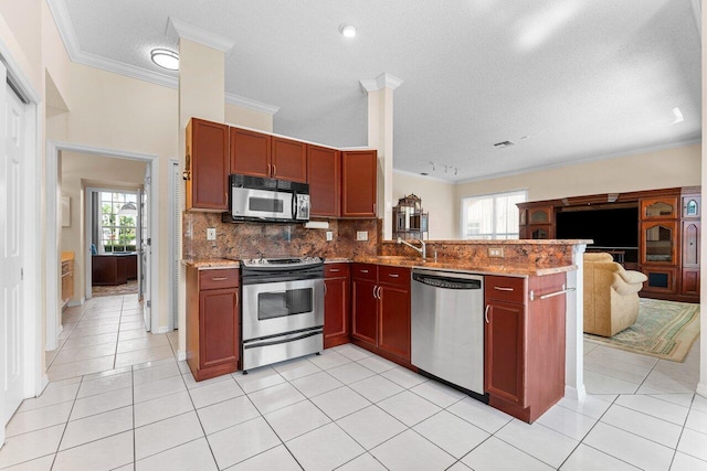 kitchen with crown molding, stainless steel appliances, light stone counters, decorative backsplash, and kitchen peninsula