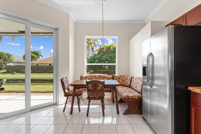 dining room featuring light tile patterned floors, crown molding, a healthy amount of sunlight, a textured ceiling, and breakfast area