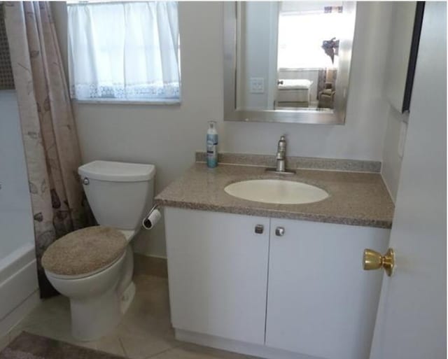 bathroom with vanity, toilet, tile patterned flooring, and a wealth of natural light